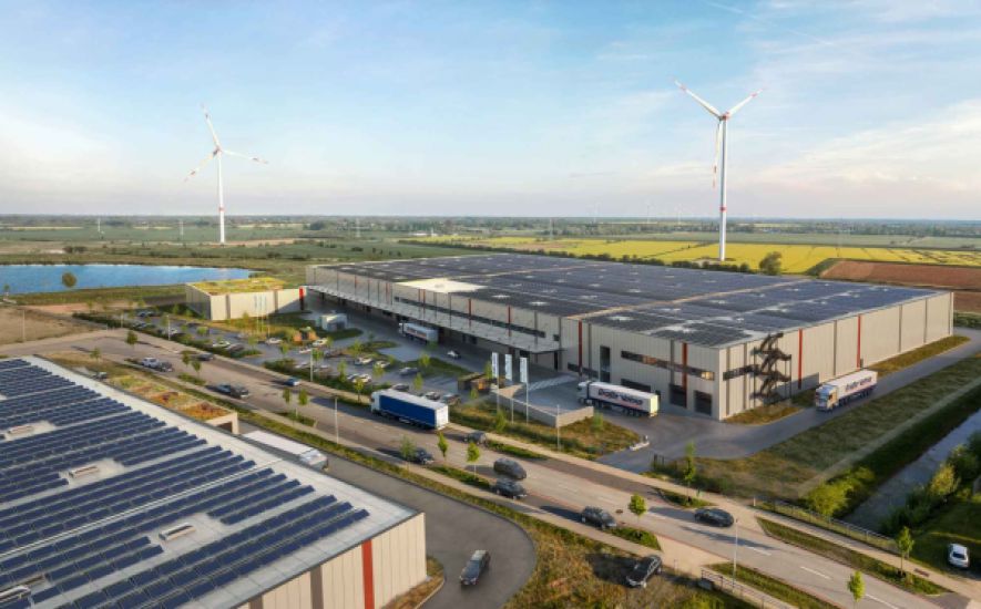 Aerial view of the logistics hall Hansalinie Bremen - Onebox. A large warehouse with solar cells on the entire roof.