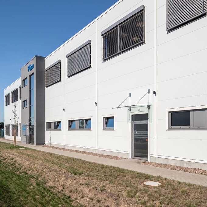 A large building is shown, which is to serve as a warehouse, production hall and office wing. A staff entrance and a main entrance can be seen, as well as various windows on the ground floor and ground floor.