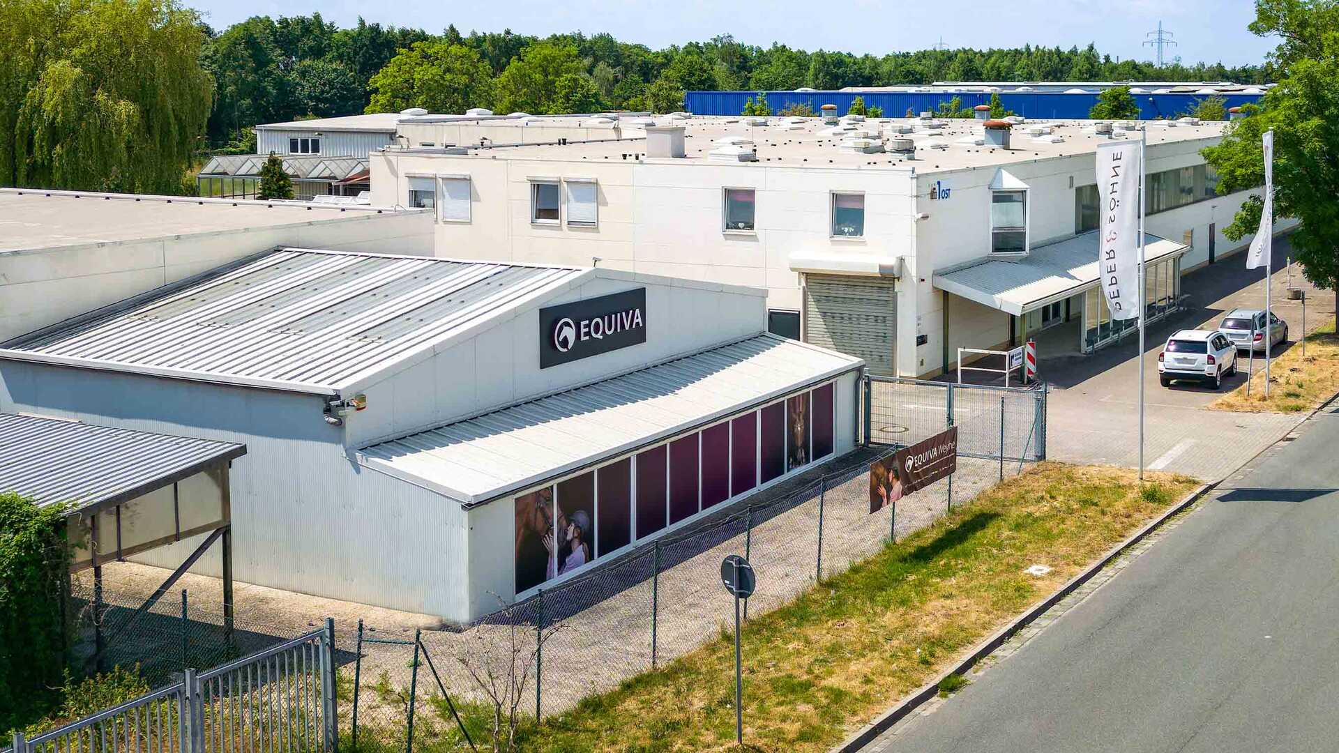 Foto der Lagerhalle. Dargestellt ist der Gewerbehof mit einer großen Lagerhalle und einem Haus mit der Aufschrift "EQUIVA".